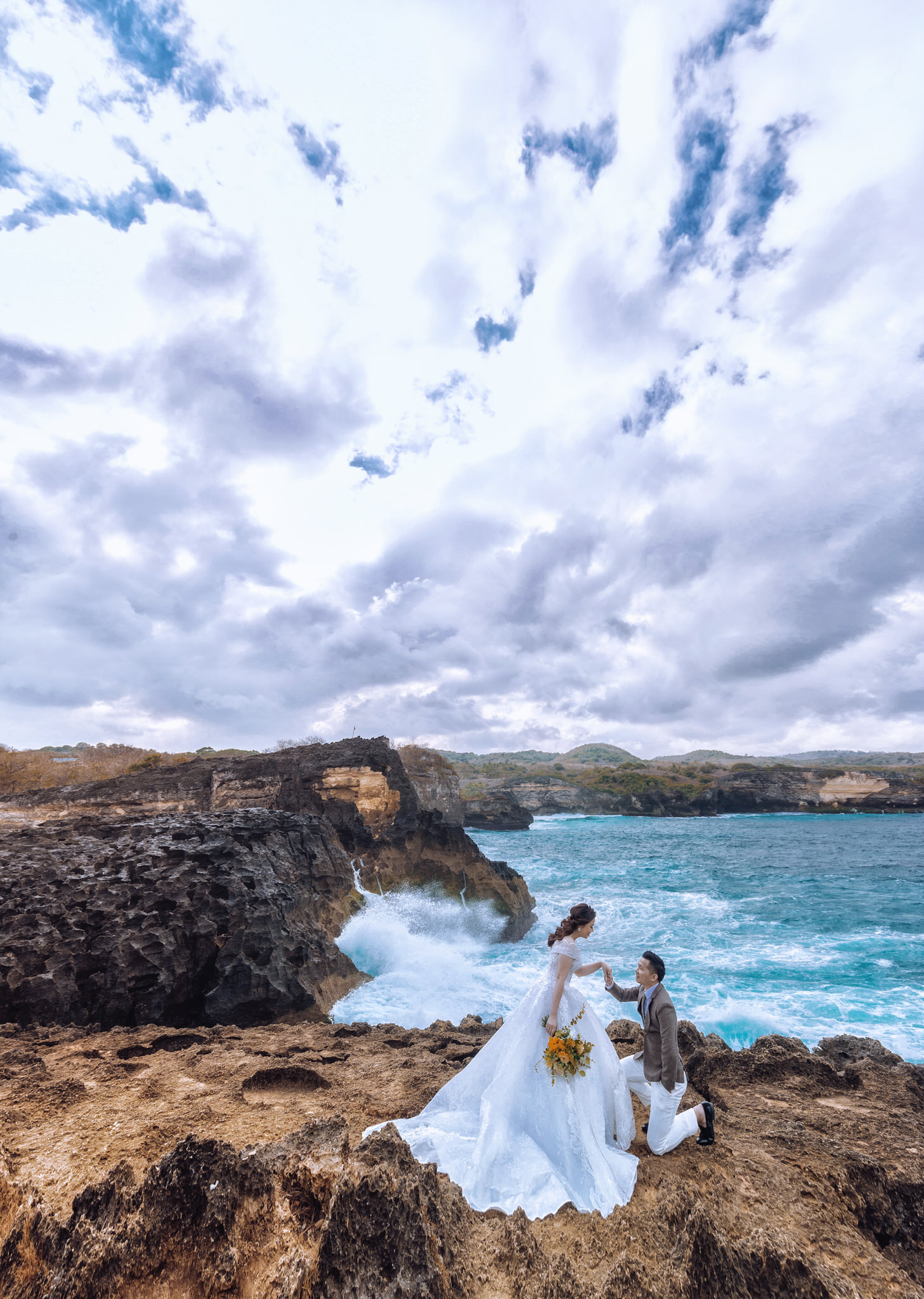 Cặp đôi chụp ảnh cưới Bali lúc hoàng hôn hùng vĩ trên vách đá tại đền Uluwatu, Indonesia.